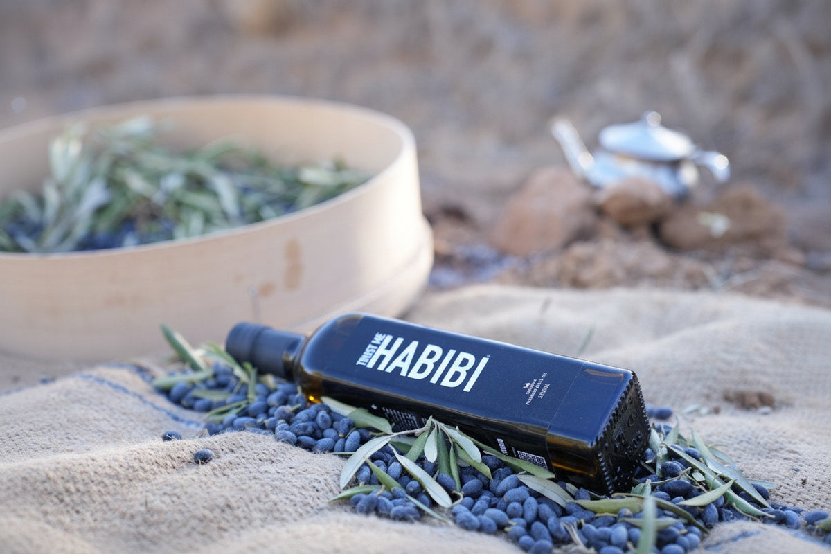 Bottle of Trust Me Habibi olive oil on a textured surface with natural background